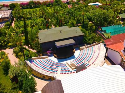 Teatro al aire libre semicircular con asientos coloridos en un entorno verde.