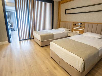 Hotel room with two single beds, wooden floor, and balcony sliding doors.