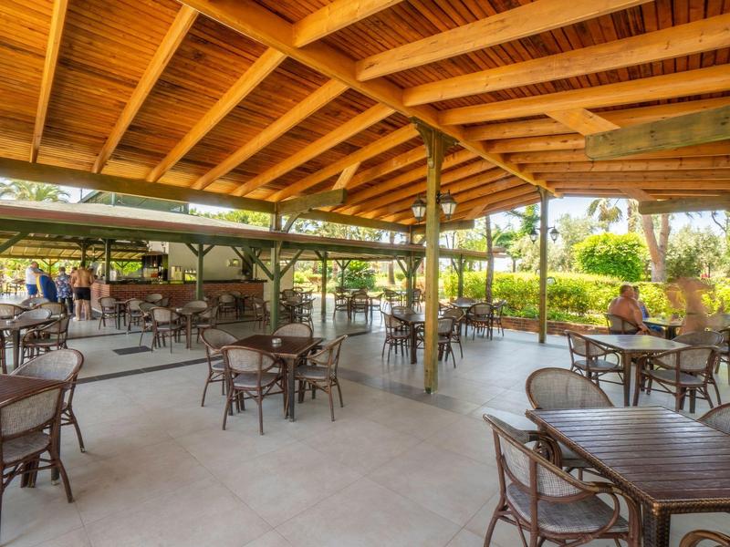 Spacious outdoor seating area with wooden roof and numerous tables and chairs.
