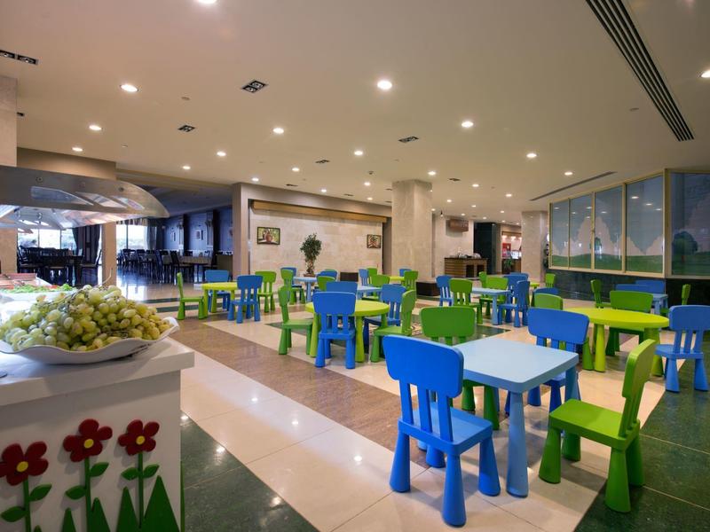 Indoor dining area with colorful blue and green chairs and tables in a bright, spacious room.