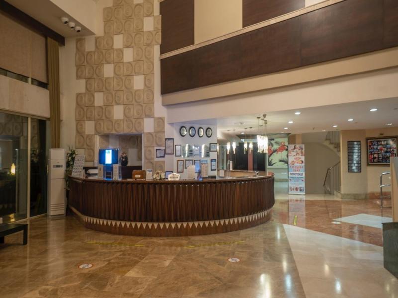 Elegant hotel reception with curved wooden desk and polished marble floor under warm lighting.