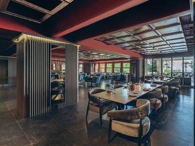 Intérieur moderne de restaurant d'hôtel avec grandes fenêtres et mobilier élégant en bois.