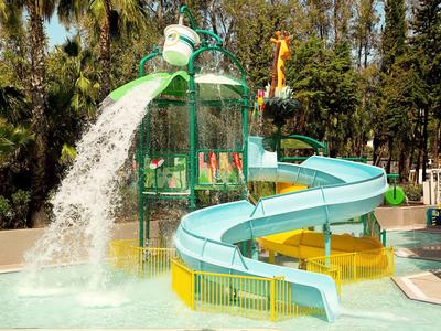 Toboggan bleu dans une aire de jeux aquatique entourée d'arbres tropicaux.