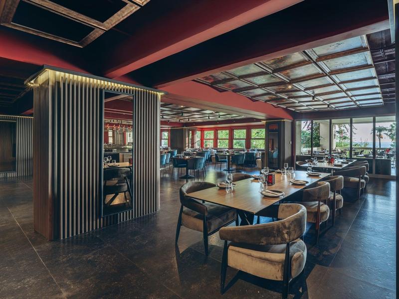 Intérieur moderne de restaurant d'hôtel avec grandes fenêtres et mobilier élégant en bois.