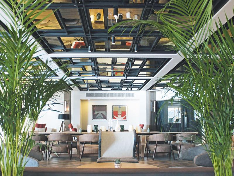 Intérieur d'un restaurant chic avec mobilier moderne et grandes plantes vertes.