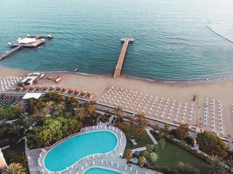 Plage aménagée avec parasols et piscine près de la mer calme.