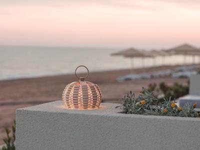 Dekorativní lucerna na zdi s výhledem na pláž a západ slunce.