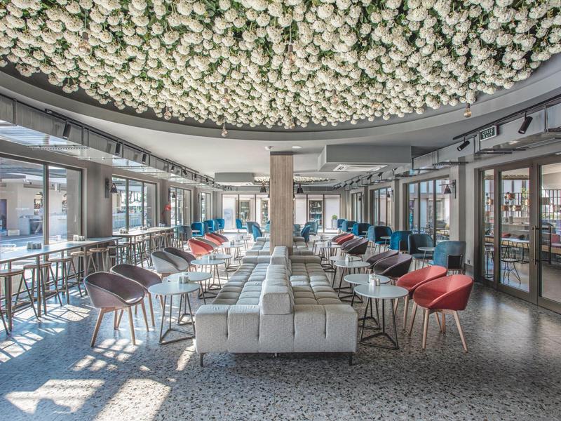 Moderní hotelová restaurace s květinami na stropě a barevným sezením.