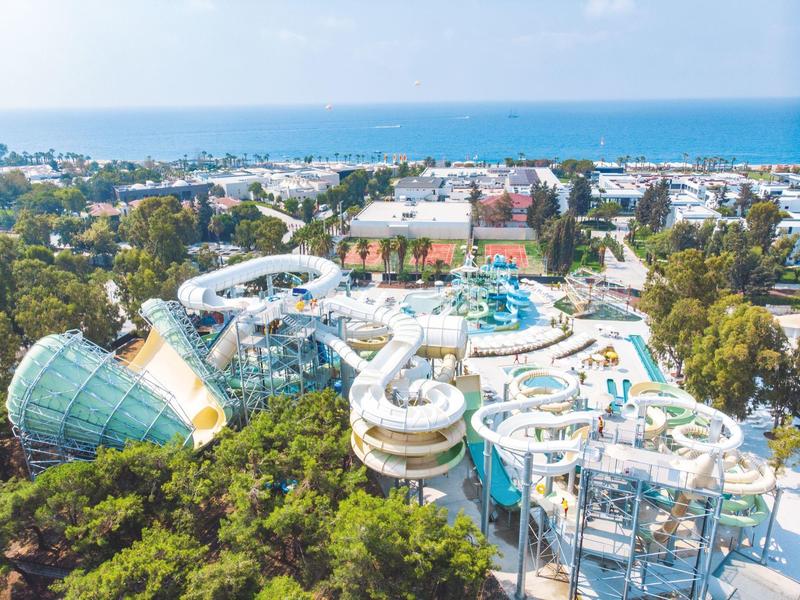Pohled na vodní park s několika skluzavkami a bazény v pobřežním městě.