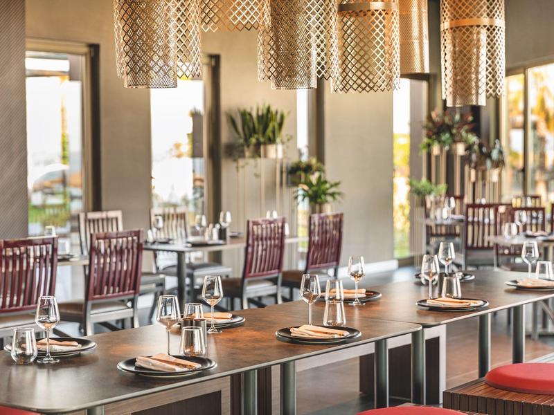 Moderní restaurace s prostřenými stoly a židlemi v teplém denním světle.