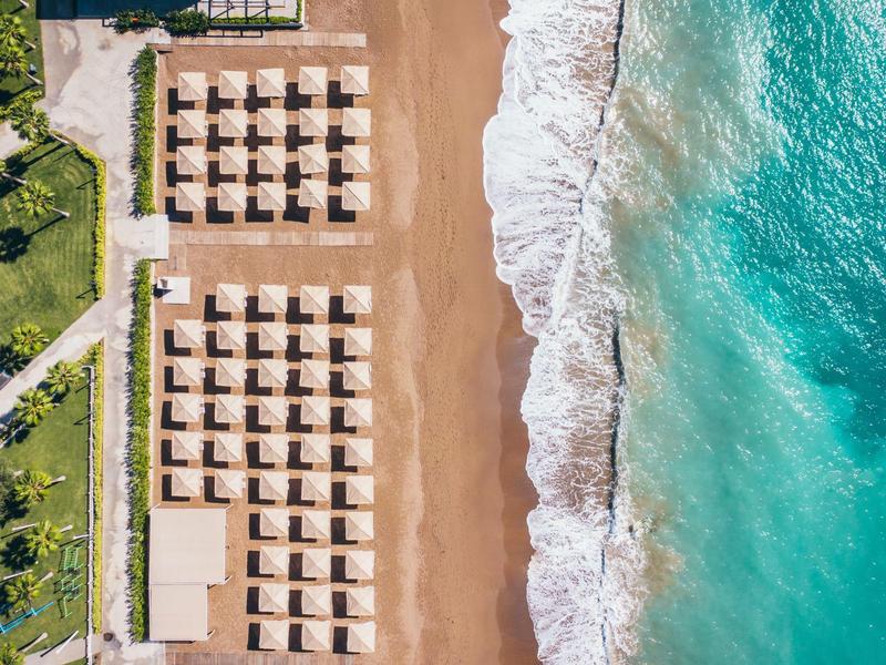 Letecký pohled na pláž s řadami slunečníků a tyrkysové moře