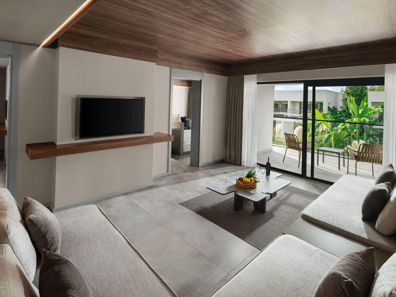 Moderner Wohnzimmerbereich mit grauem Sofa, Flachbildfernseher und großer Glasschiebetür zum Balkon.