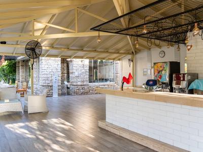 Offene Veranda mit hellem Holzboden, weißer Theke und gemütlichen Sitzbereichen unter Holzdecke.