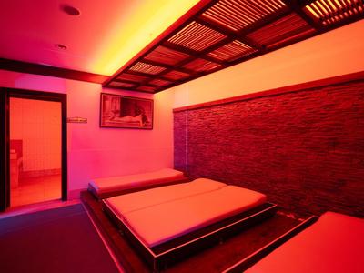 Ein Zimmer mit zwei Betten, warmem rotem Licht und dekorativem Decken- und Wanddesign.