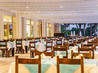 Großer Speisesaal mit vielen Holztischen und Stühlen, gedeckt mit weißen Tüchern und blauen Servietten.