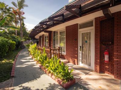 Esterno di un hotel con aiuole, pareti in mattoni e un sentiero al mattino