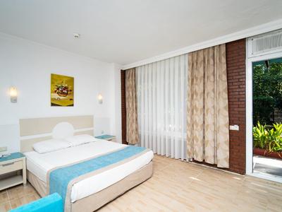 Helles Schlafzimmer mit Doppelbett, blauen Akzenten, Holzfußboden und Blick auf einen Garten.