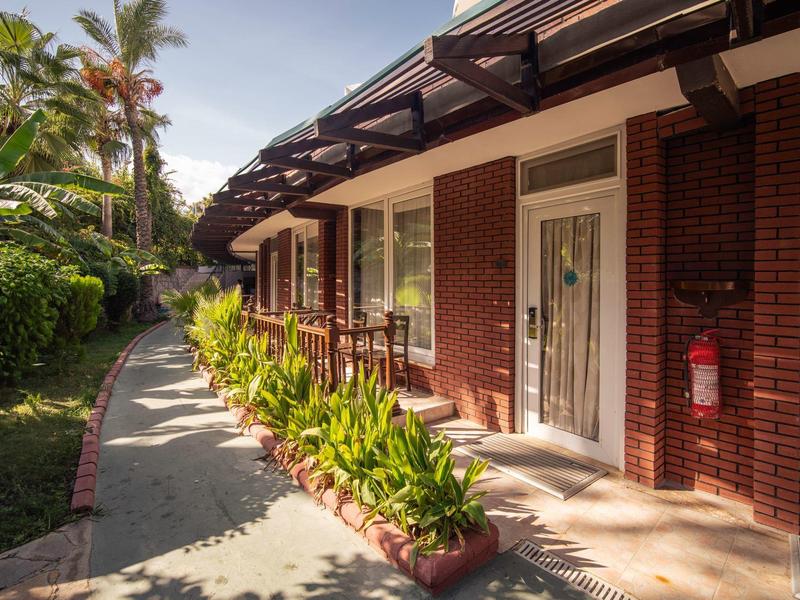 Einwegiger Weg entlang eines roten Backsteingebäudes mit Pflanzen und Sonnendach.