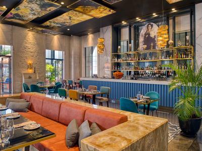 Modern ingericht restaurant met oranje bank en blauwe bar bij warm licht.