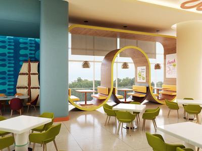 Moderne hotellounge met gele hangstoelen, groene stoelen en grote raampartijen.