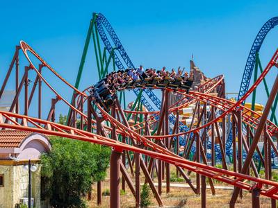 Achtbaan met rode en blauwe rails tegen een heldere blauwe lucht in een pretpark