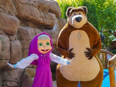 Twee mensen in mascottekostuums voor een rotsachtig decor met trappen.