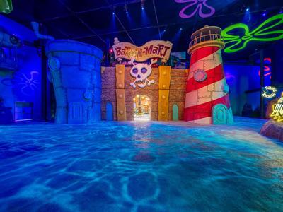 Kleurig verlicht kinderzwembad met piratenscheepsdecoraties en vuurtoren in binnenzwembad