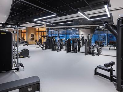 Moderne fitnessruimte met verschillende trainingsapparaten en grote ramen.