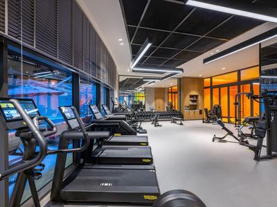 Moderne fitnessruimte met loopbanden, crosstrainers en krachtapparaten in een lichte, ruime kamer.