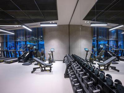 Moderne sportschool met dumbbells, gewichten en spiegels in een hotel.