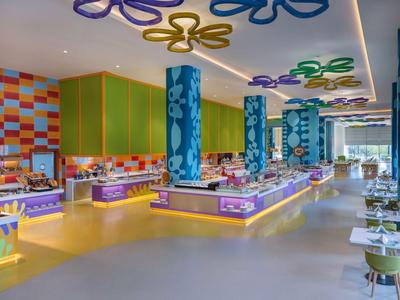 Een modern, kleurrijk buffetrestaurant met bloemenpatronen op zuilen en plafond.