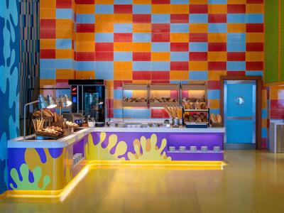 Kleurrijk buffet met diverse gerechten in een modern restaurant met levendige muurschilderingen.