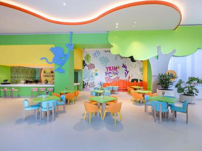 Kleurrijke gemeenschappelijke ruimte met tafels, stoelen en speelse wanddecoraties in een hotel.
