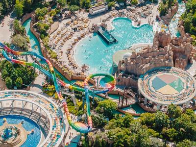 Kleurrijk waterpark met zwembaden, glijbanen en omgeven door groen