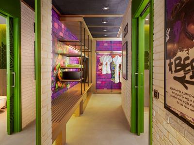 Moderne hotelgang met groene deurkozijnen en kleurrijke wanddecoraties.