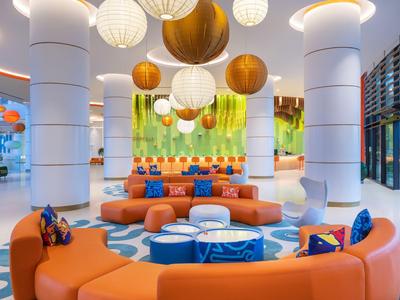 Moderne lounge met oranje zitmeubilair en hangende bolvormige lampen in een hotel.