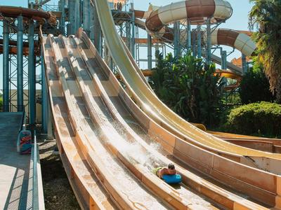 Meerdere waterglijbanen in een waterpark bij helder zonlicht.