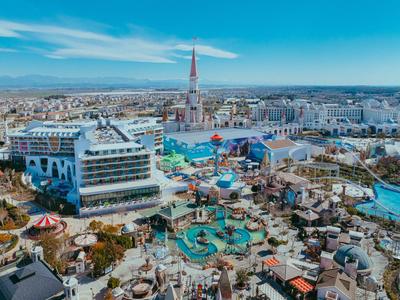 Groot waterpark met veel zwembaden, glijbanen en omliggende gebouwen onder een heldere hemel