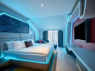 Modern hotelkamer met futuristische verlichting en groot bed.