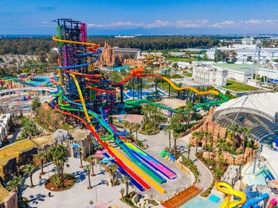 Wasserpark mit bunten Rutschen und Liegebereichen bei sonnigem Wetter mit Bergblick.