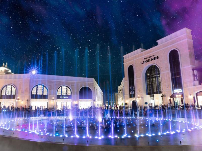 Verlichte fontein voor een gebouw in een nachtsvakantieomgeving.