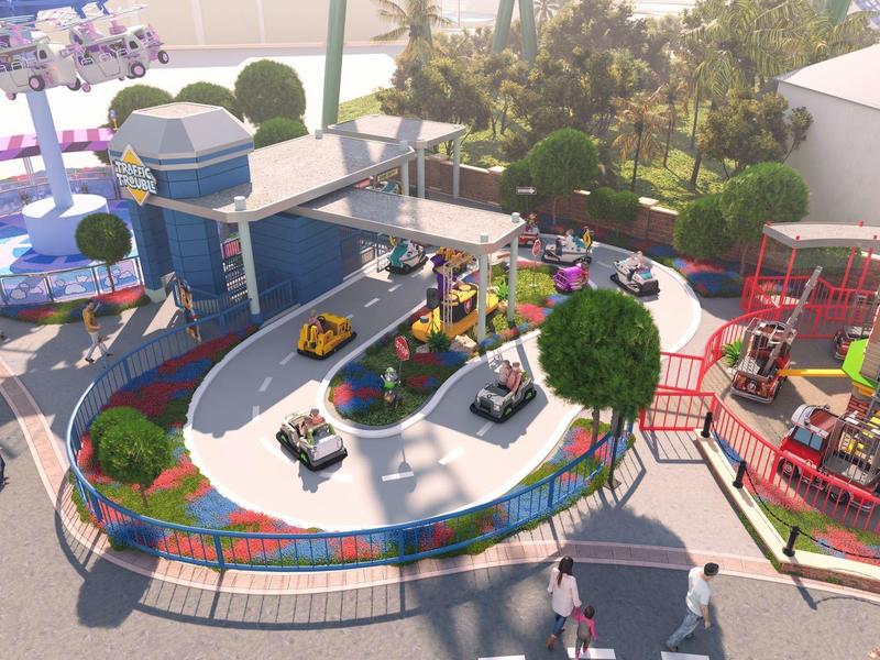 Model van een miniatuurspoorlijn met kleurrijke treinen en gebouwen buiten, omgeven door hekken.