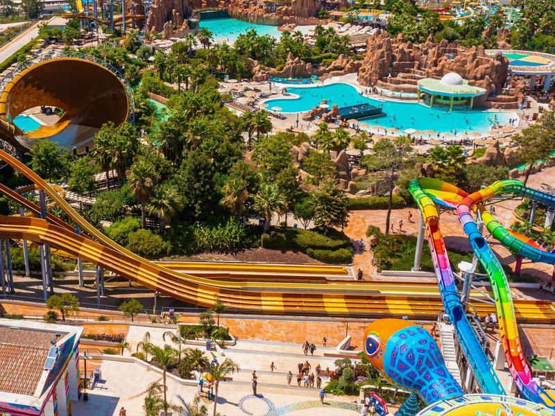 Waterpark met grote glijbanen en meerdere zwembaden in een groene omgeving.