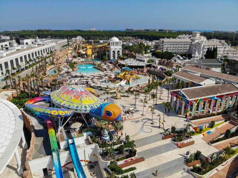 Groot waterpark met glijbanen, zwembaden en kleurrijke attracties bij een resort op een zonnige dag.
