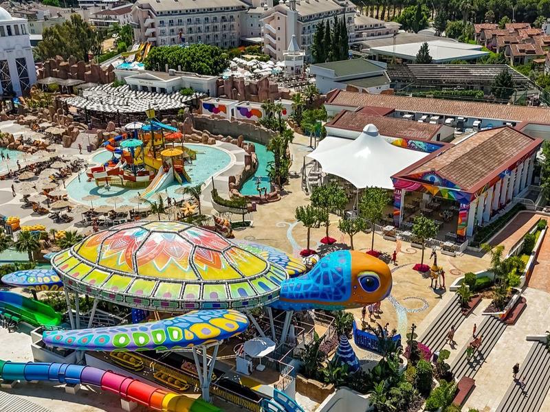 Overzicht van een groot waterpark met kleurrijke glijbanen en zwembaden bij een hotelresort.