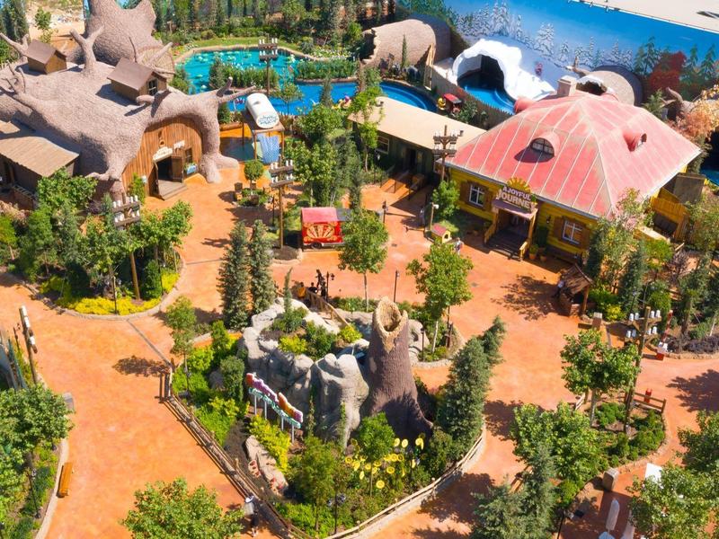 Uitzicht op een kleurrijk vakantieoord met zwembad, exotische architectuur en weelderig groen.