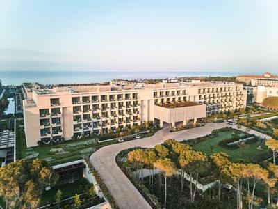 Grand bâtiment d'hôtel à plusieurs étages entouré d'arbres et d'une allée.