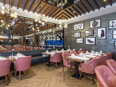 Restaurant moderne avec des chaises roses, parquet en bois et décorations murales dans un hôtel.