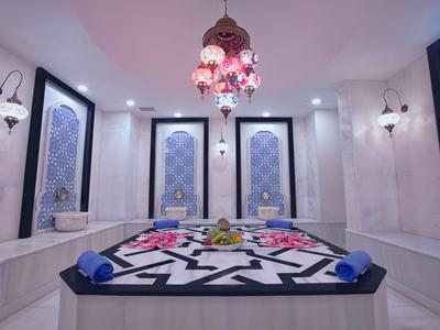 Traditionelles türkisches Hammam mit Marmorwänden, kunstvollen Fenstern und einem zentralen Ruhebereich.
