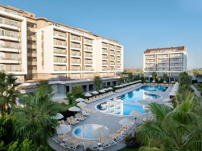 Complexe hôtelier moderne avec deux bâtiments et une grande piscine extérieure sous un ciel dégagé.